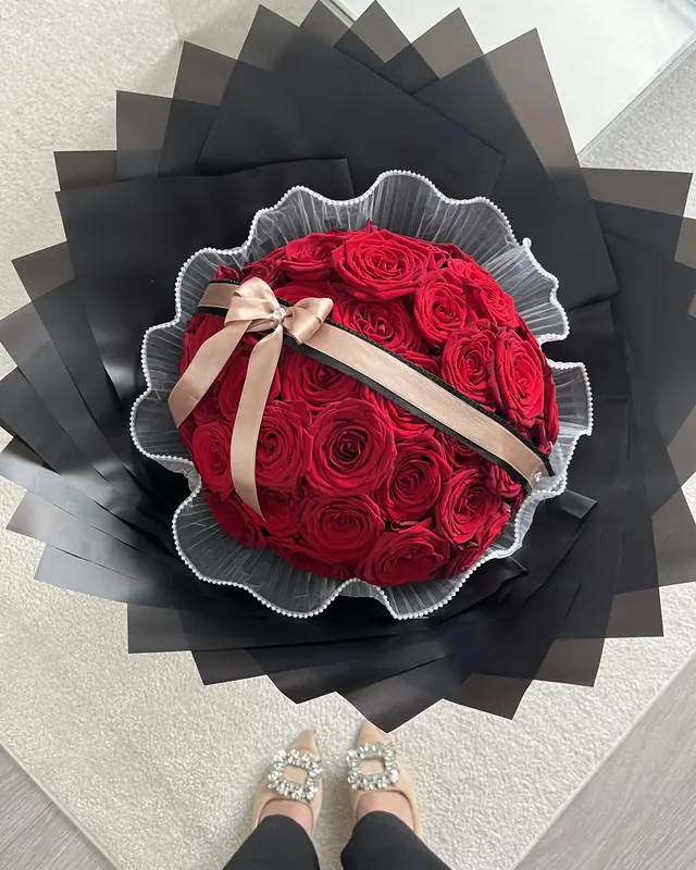 Large red rose bouquet with a satin bow in black wrap by Amorella Flower Boutique
